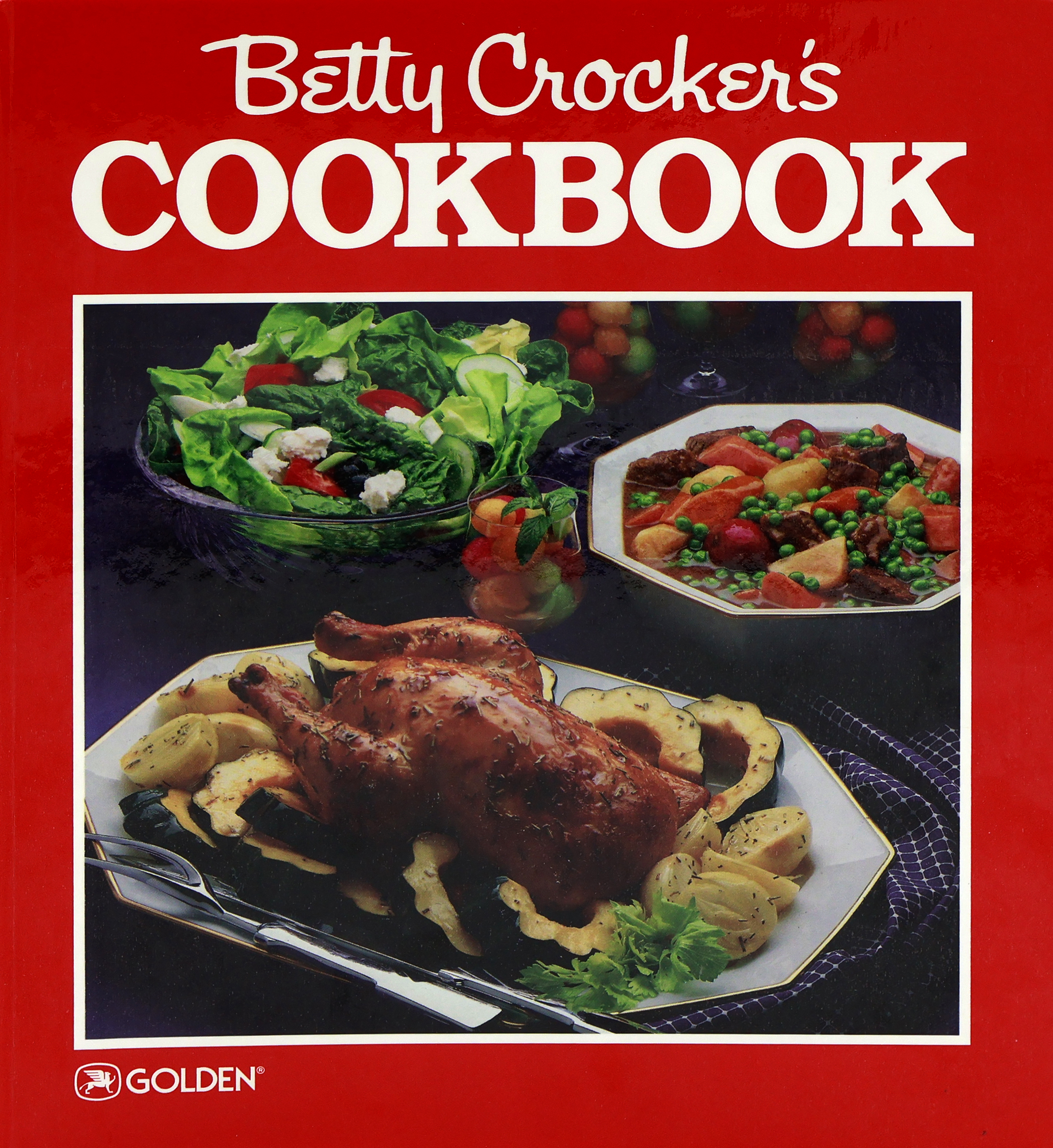 Cover of the 1986 Betty Crocker Cookbook with a red cover that has a roast chicken surrounded by acorn squash slices, tossed salad, beef stew, and melon balls in clear glass stemware.